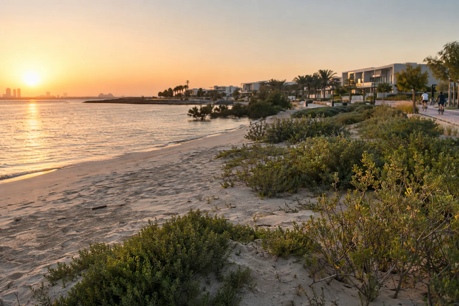 Natural shoreline of Al Hudayriat Island with coastal vegetation and recent low-rise homes in the background