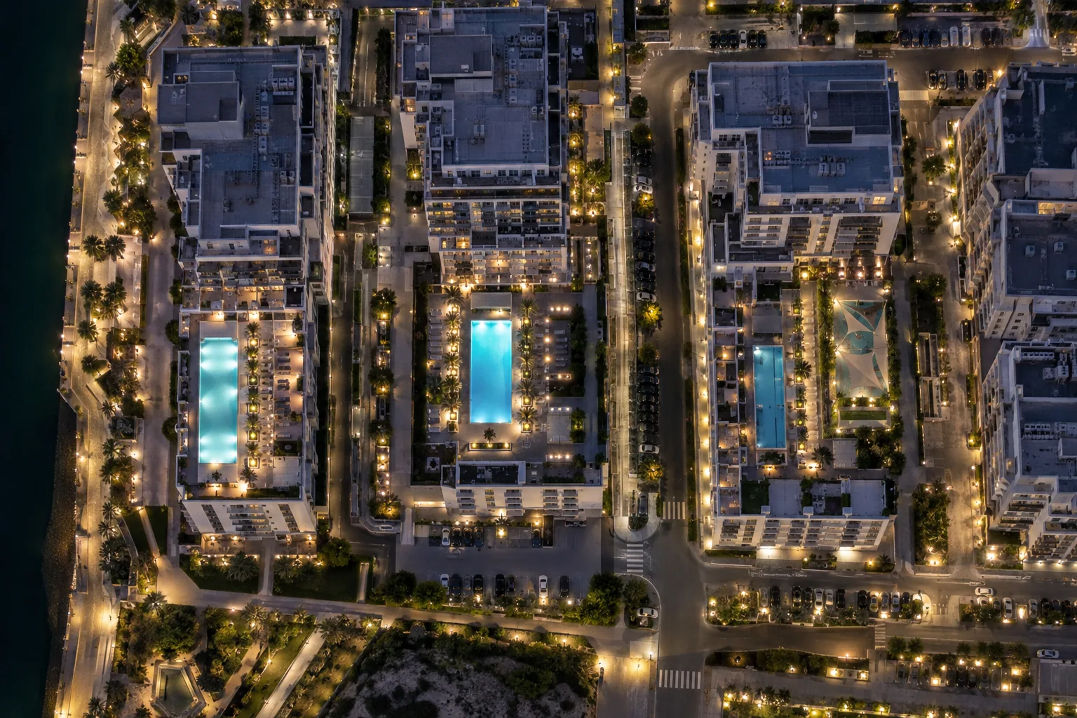 Overhead night view of neighbouring residences on Yas, lit pools and partly dark windows