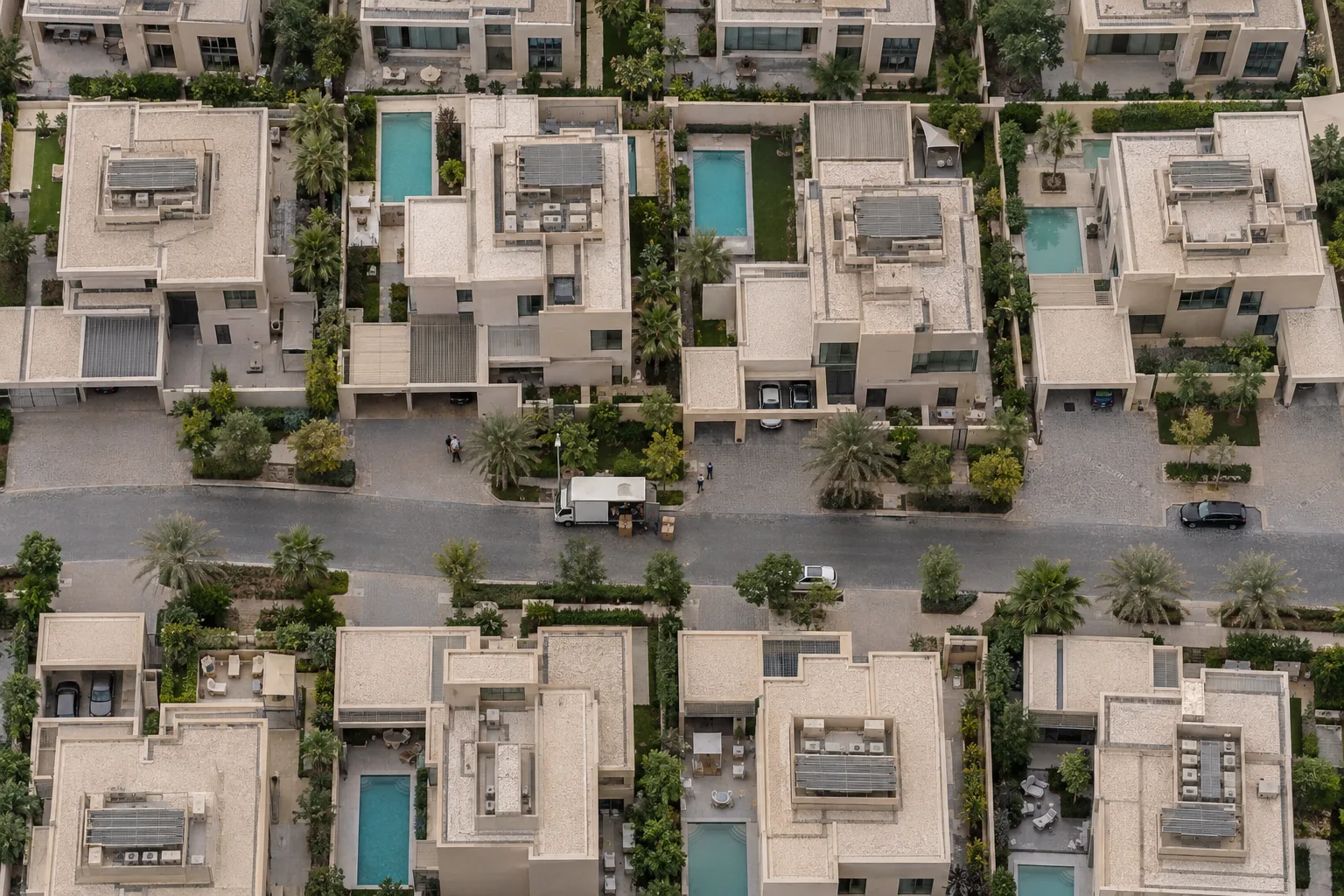 Aerial view of a set of recent villas on Yas Island, with private pools and a moving truck in front of a house
