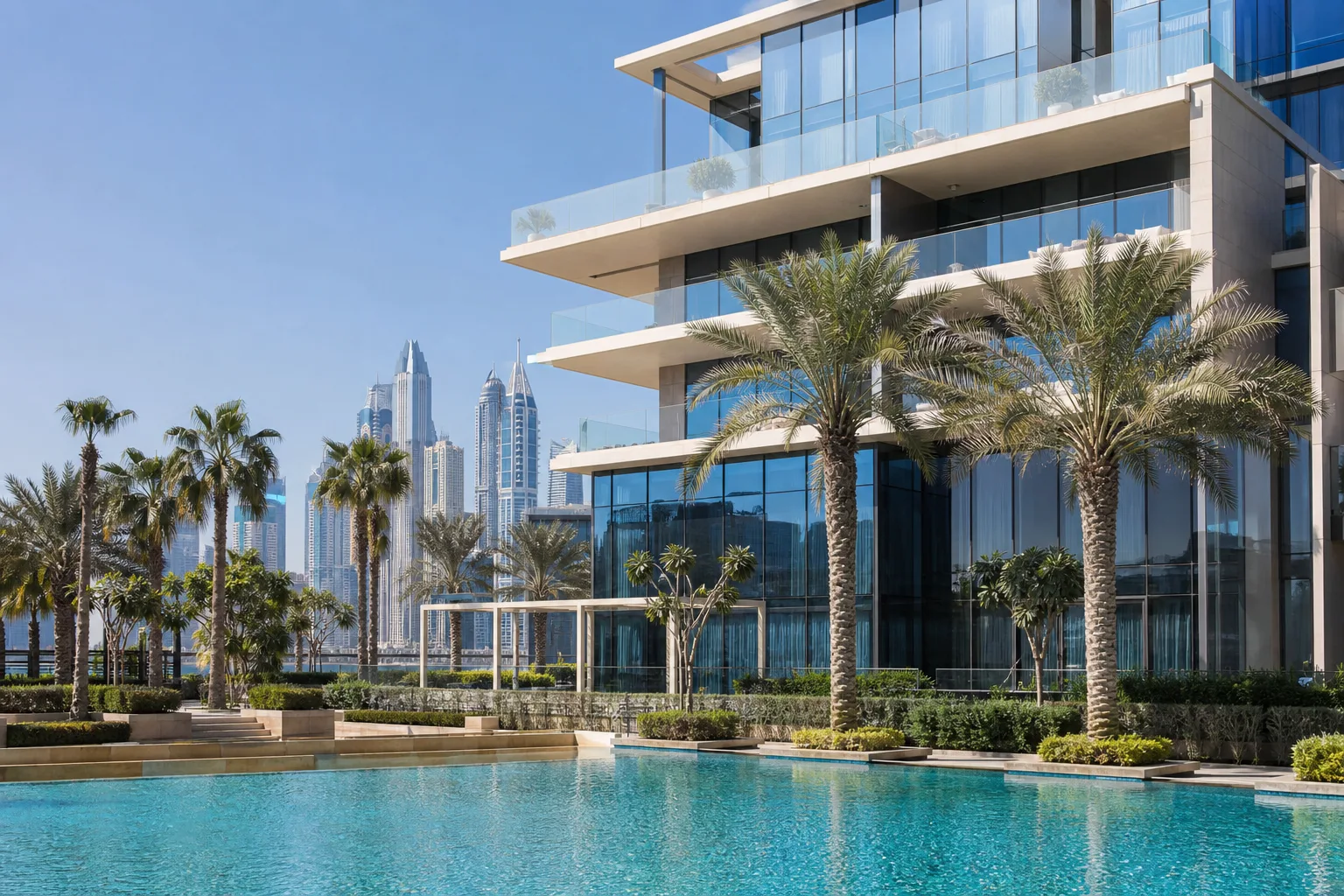 Edificio residencial de alta gama en zona freehold de Dubái con palmeras y fachada de cristal al sol
