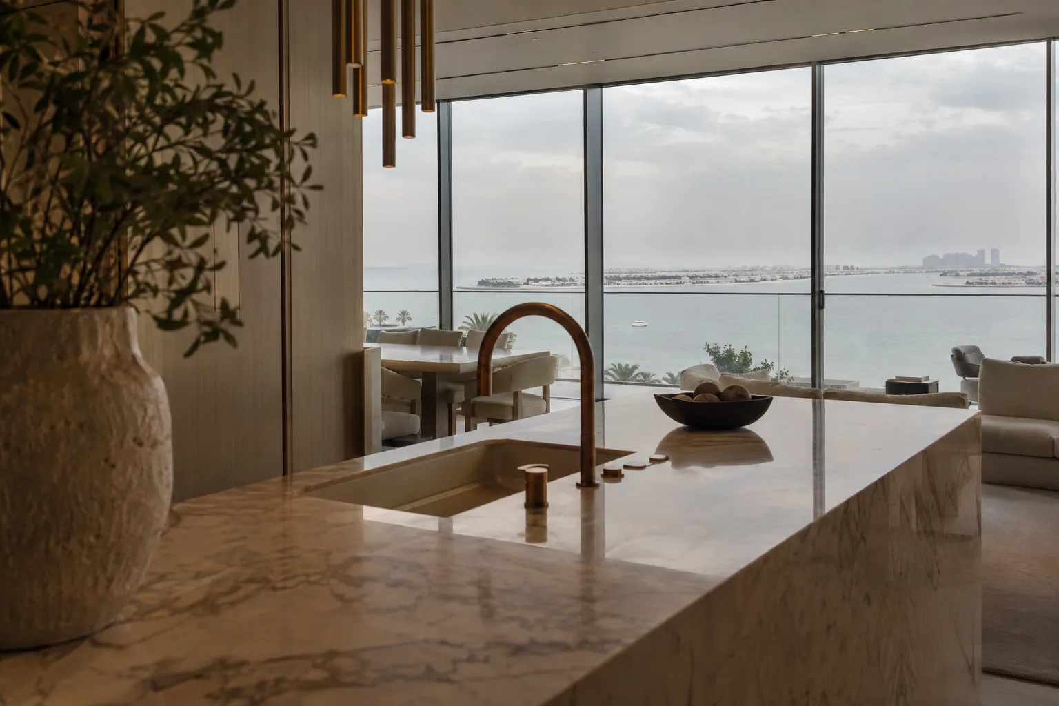 Marble kitchen island with bronze finishes in an ultra-luxury Dubai apartment, floor-to-ceiling windows overlooking the sea