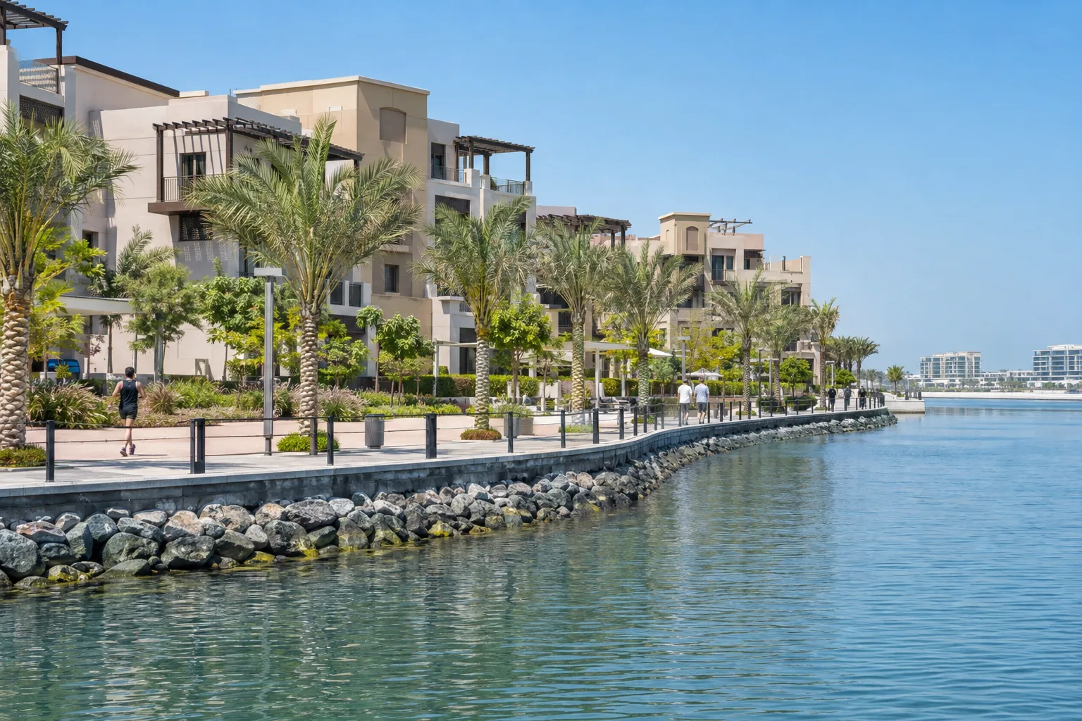 Waterfront promenade on Yas Island at midday, with residents in the distance and low-rise residential buildings