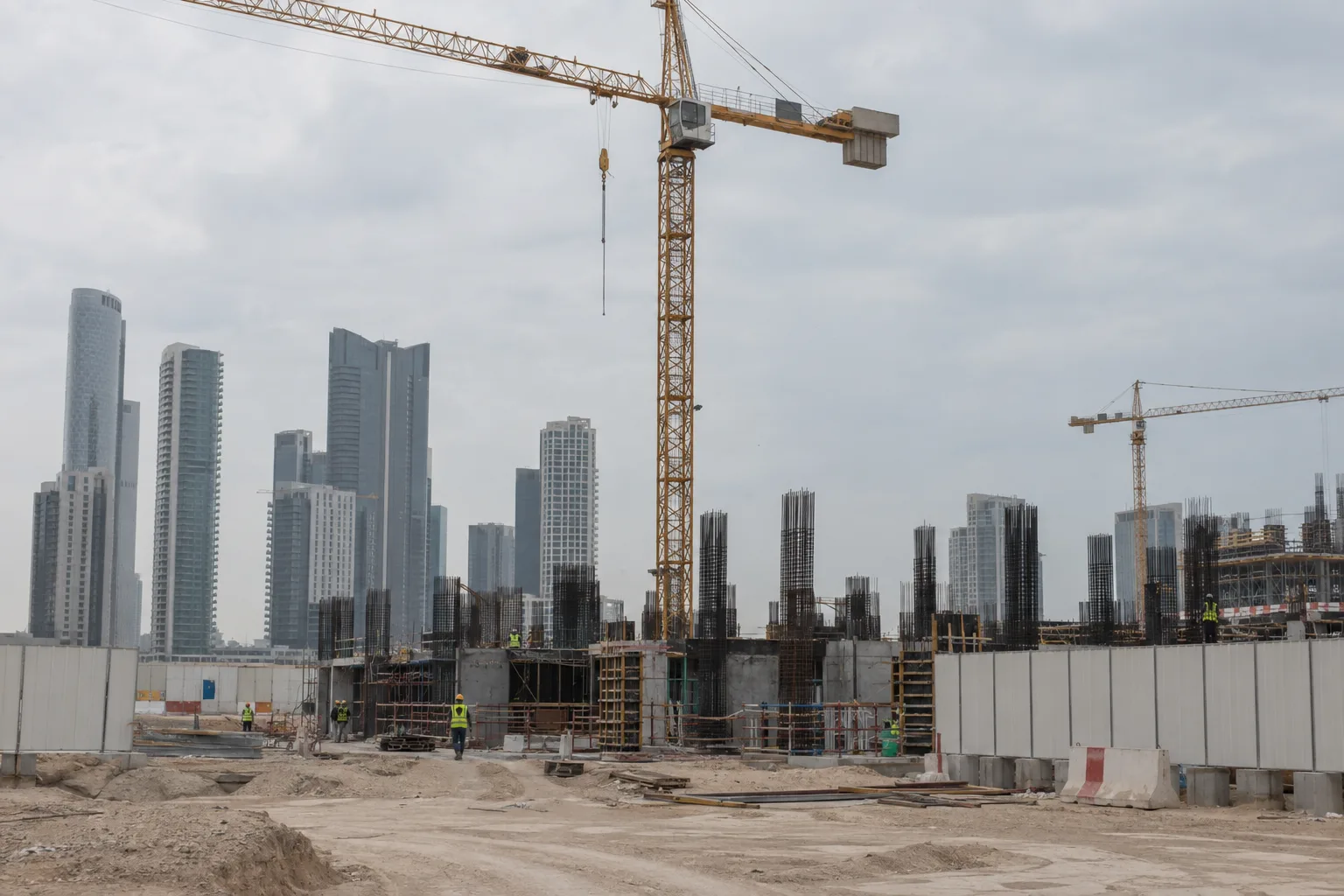 Residential tower construction site at foundation stage on Reem Island, crane and workers seen from a distance