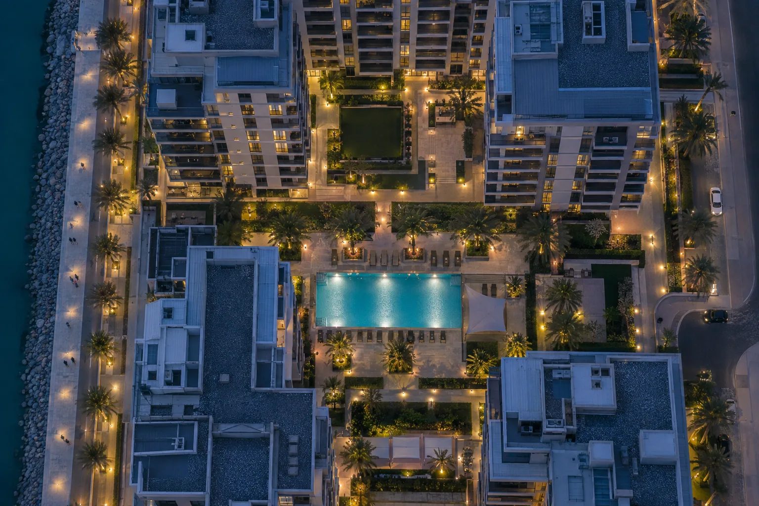 Overhead view of an apartment complex on Yas Island at blue hour, with pool and lit walkways