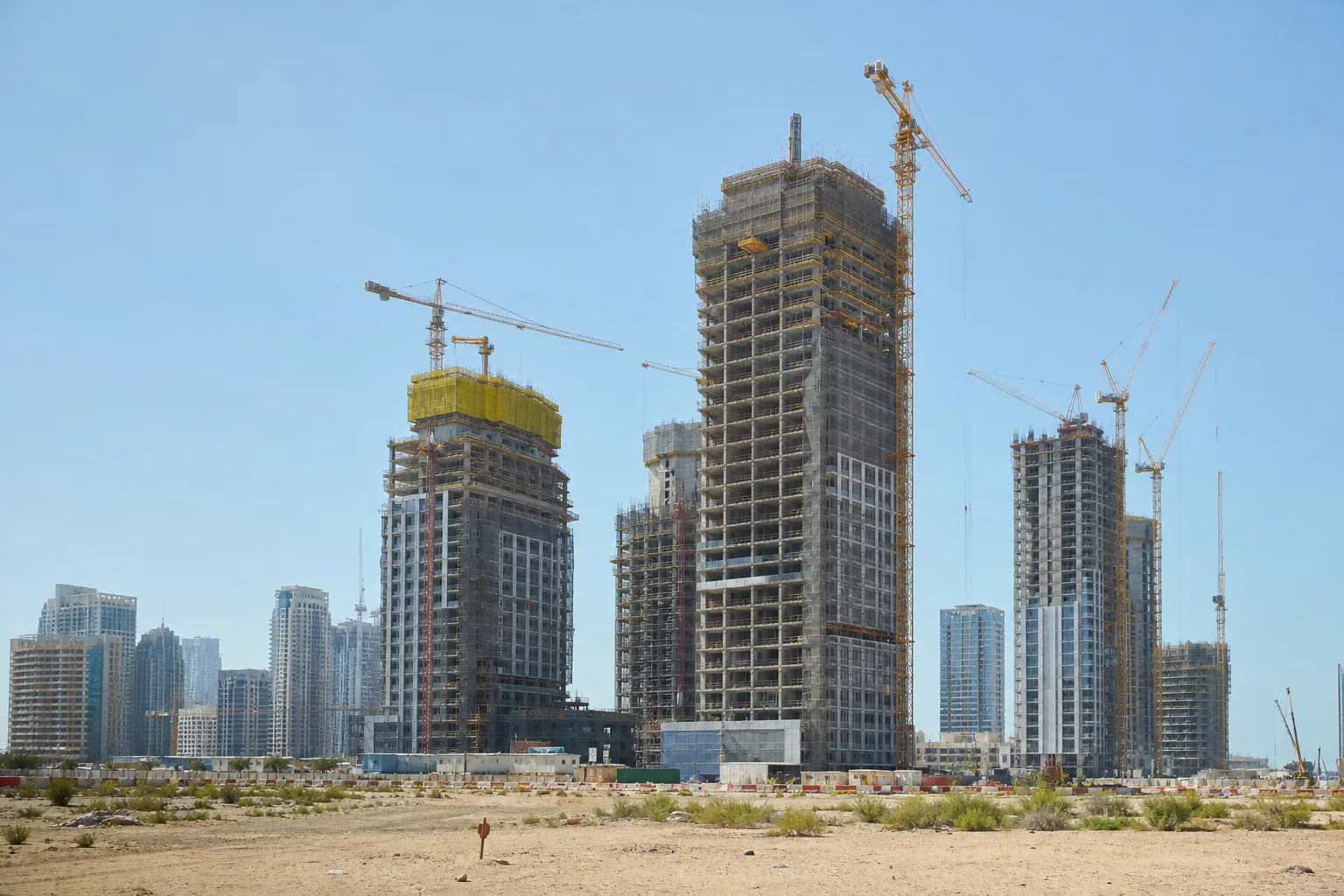 Chantier de construction de tours résidentielles neuves dans un quartier émergent de Dubaï sous un ciel dégagé